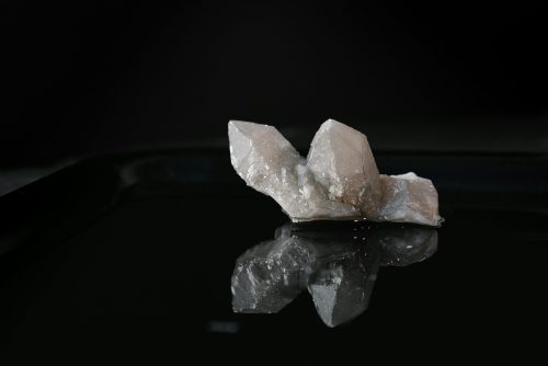 A striking quartz crystal displayed on a glossy black surface, highlighting its natural beauty and mystique.
